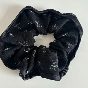 Detail of black lace scrunchie with white bow patterns and Hand Made woven label
