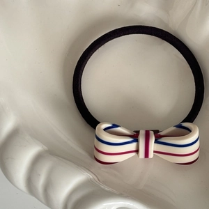 Striped acetate bow hair tie with navy blue and pink stripes on white resin finish
