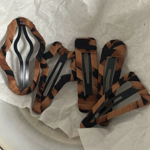 Set of leopard print snap hair clips and square barrettes on a white paper background