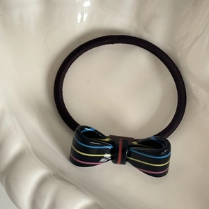 Close-up of black elastic hair tie with a colorful striped acetate bow decoration