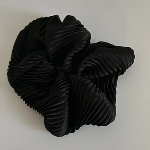 Gros plan d'un chouchou en satin plissé noir avec texture brillante et ondulée