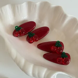 Set mit vier süßen roten Kirsch-Haarspangen in einer Muschelschale mit Glanzeffekt