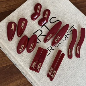 Flat lay of wine red resin hair clips with gold lettering on a vintage textured book