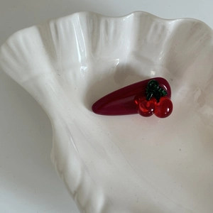 Detailansicht einer Vintage dunkelroten Kirsch-Haarklammer auf einer weißen Schale