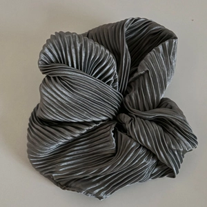 Gros plan sur un chouchou en tissu plissé gris foncé avec texture ondulée et fini satiné