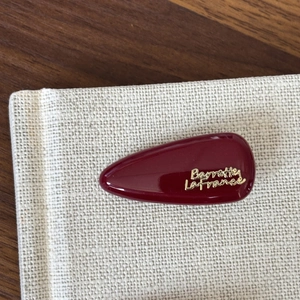 Macro shot of a glossy burgundy red hair clip with golden Barrette La France lettering