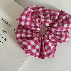 Pink plaid fabric scrunchie with large ruffles on a white background and magazine