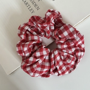Detail of a large red and white gingham scrunchie on a white book for a minimalist look