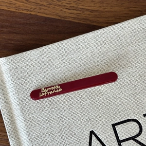 Close-up of a burgundy French hair clip with elegant golden lettering and smooth texture