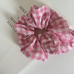 Close-up of pink and white plaid fabric scrunchie on a decorative magazine background