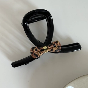 Close-up of black leopard print bow hair claw clip with golden metal accents