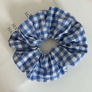 Detail of blue and white gingham hair scrunchie showing fabric texture and pleated design