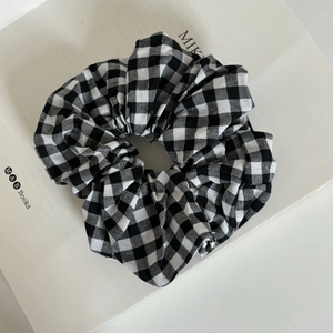 Macro view of large black and white gingham fabric scrunchie on a white book prop