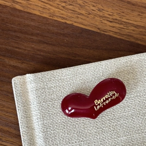 Elegant wine red heart-shaped hair clip with gold engraved text on textured fabric