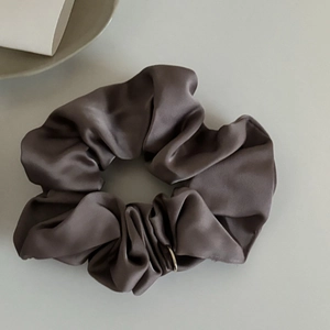 Vue détaillée du chouchou en satin marron foncé avec texture soyeuse et plis élégants