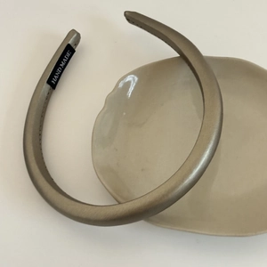 Close-up of champagne satin headband with handmade label on a ceramic tray