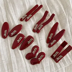 Deep wine red French hair clips set with gold logo lettering on white fabric