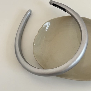 Detail of silver satin padded headband with hand made label on a ceramic plate