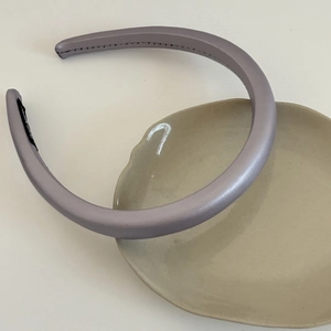 Detailed close-up of a lilac purple satin padded headband on a decorative white ceramic dish