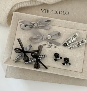 Détail de nœuds en satin gris et barrettes à perles pied-de-poule sur plateau de vente