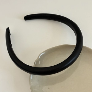 Close-up of thick black satin sponge headband showing smooth texture and padded design