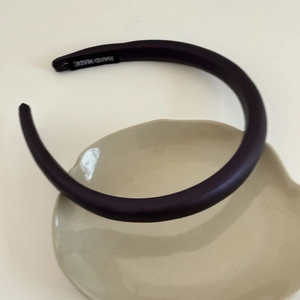 Detailed view of dark leather headband with handmade label on beige ceramic tray