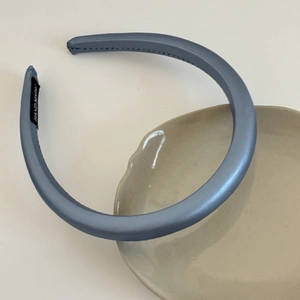 Close-up of light blue satin padded headband with handmade label on ceramic plate