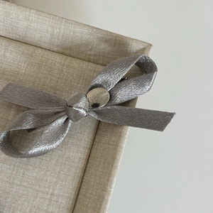 Gros plan détaillé d'un nœud papillon en satin gris avec plaque Believe In Yourself gravée