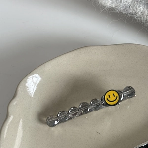 Détail de la pince à cheveux avec perles en résine transparente et motif smiley jaune