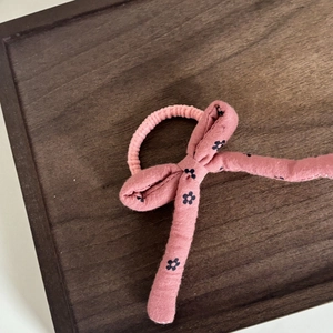 Elastico per capelli rosa con fiocco floreale per ragazze su un vassoio di legno
