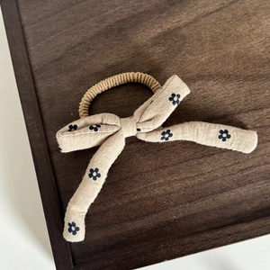 Dettaglio di un elastico per capelli beige con fiocco su vassoio in legno