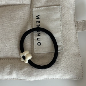 Élastique à cheveux noir minimaliste avec breloque fleur en résine sur lin