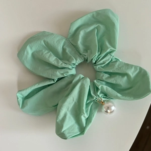 Détail du chouchou floral vert menthe avec texture de tissu et pendentif perle blanche