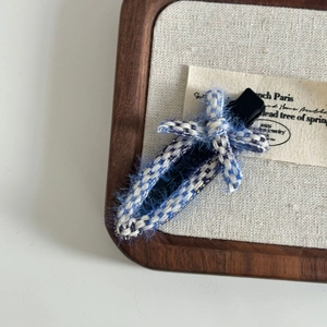 Blue woven bow hair clip with French vintage style on a white background minimalist display