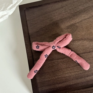 Dettaglio del fiocco rosa per capelli con motivo floreale su vassoio in legno rustico
