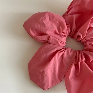 Gros plan détaillé du chouchou en tissu plissé moelleux en rose corail doux