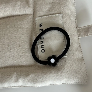 Gros plan d'un élastique à cheveux noir avec une fleur noire mignonne au centre blanc