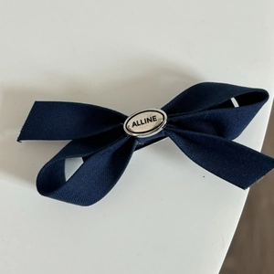 Detailed macro view of navy blue satin bow hair clip with silver engraved metal buckle