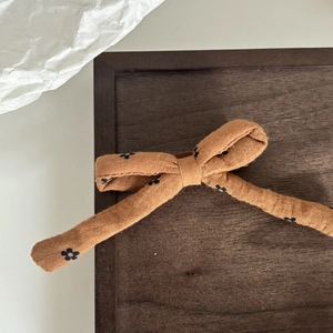 Dettaglio di fiocco per capelli arancione con piccoli fiori neri su legno scuro