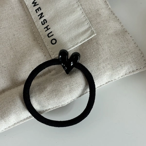 Gros plan sur un élastique à cheveux noir avec un pendentif coeur brillant sur toile