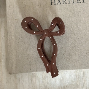 Détail d'une pince à cheveux vintage marron foncé avec un nœud élégant à pois blancs