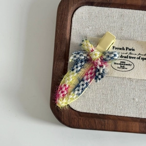 Detailed macro view of the colorful tweed fabric texture on the woven metal hair clip
