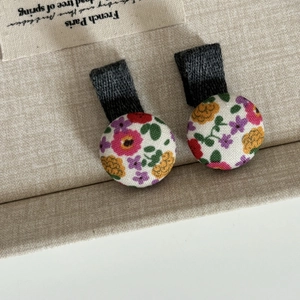 Gros plan de barrettes à boutons en tissu fleuri avec rubans à texture gaufrée