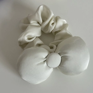 Detailed view of large white satin bow scrunchie featuring smooth silk texture and sheen