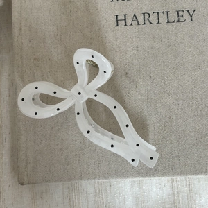 Détail d'une grande pince à cheveux blanche à pois avec nœud papillon en acétate