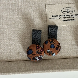 Détail des barrettes en tissu à motif floral vintage sur un plateau beige texturé