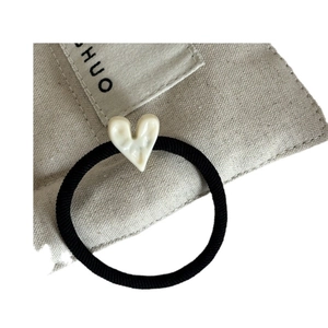 Élastique à cheveux noir avec breloque en forme de cœur blanc crème sur toile beige