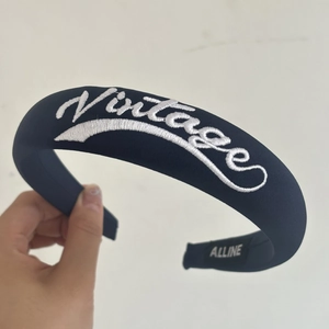 Close-up of navy blue padded headband featuring white Vintage embroidery and fine texture