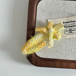 Macro shot of yellow and white tweed woven hair clip with delicate fringe detail
