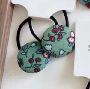 Détail d'un élastique en tissu à fleurs avec petites fleurs rouges et blanches sur vert
